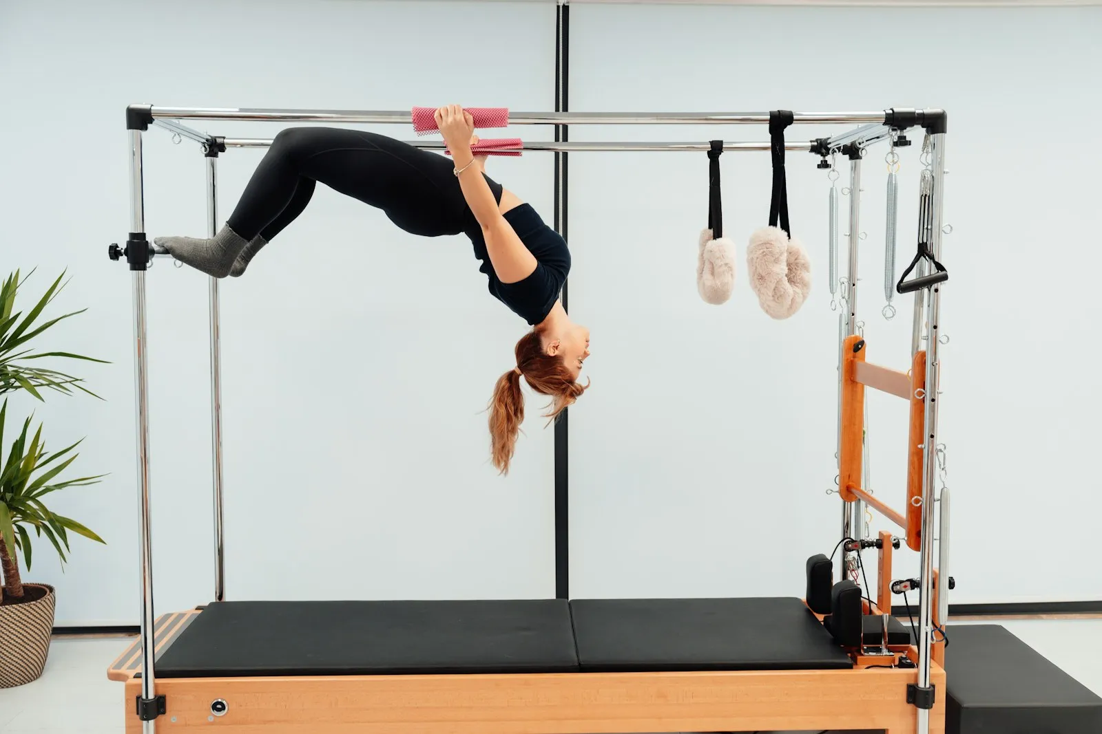 A woman arching backwards over the bar of a Pilates tower