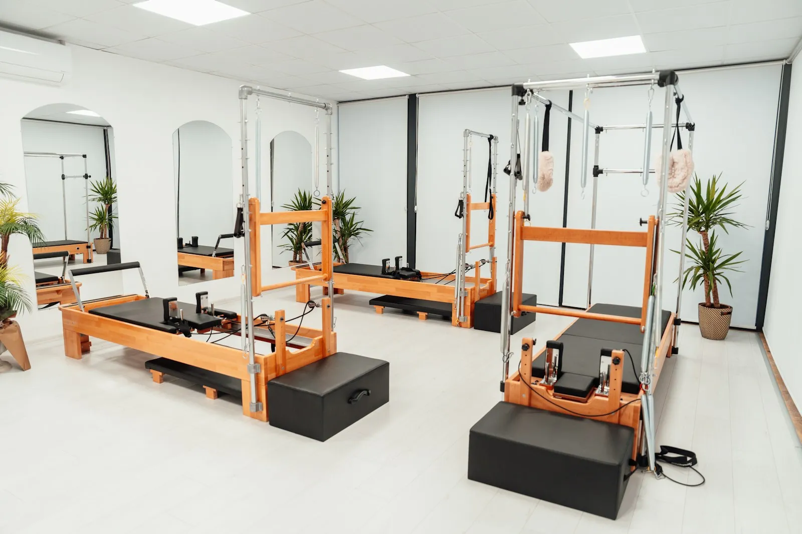 An empty Pilates studio with wooden reformers and a tower